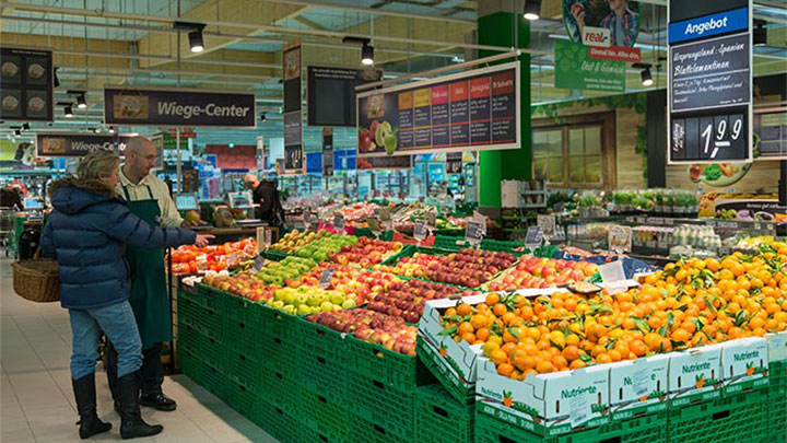 Clientes observam frutos no Real, iluminados por iluminação Philips de supermercados
