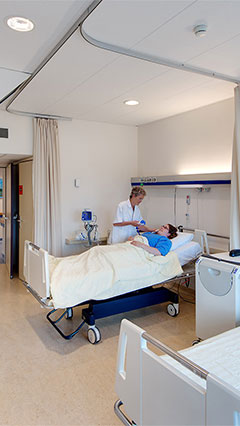Uma enfermeira controla a sua paciente num quarto de doentes do UMCG, iluminado através da iluminação economizadora Philips