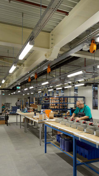Um funcionário trabalha na área de produção do Venco Campus, iluminado brilhantemente graças à iluminação industrial Philips