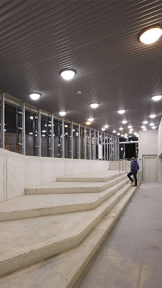  Homem a subir escadas na garagem Eiteren iluminada por iluminação Philips