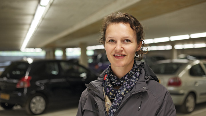  Mulher a sorrir em frente aos automóveis na garagem Eiteren iluminada por iluminação Philips