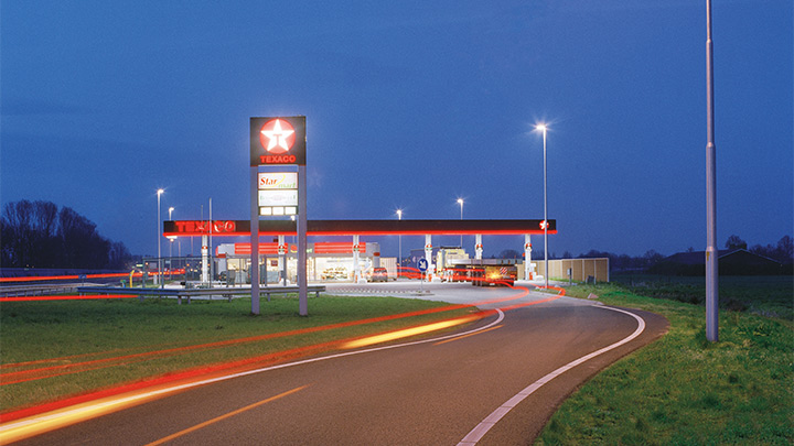 Um posto de gasolina da Texaco na saída da autoestrada, iluminado de forma atraente ao anoitecer – iluminação exterior cativante