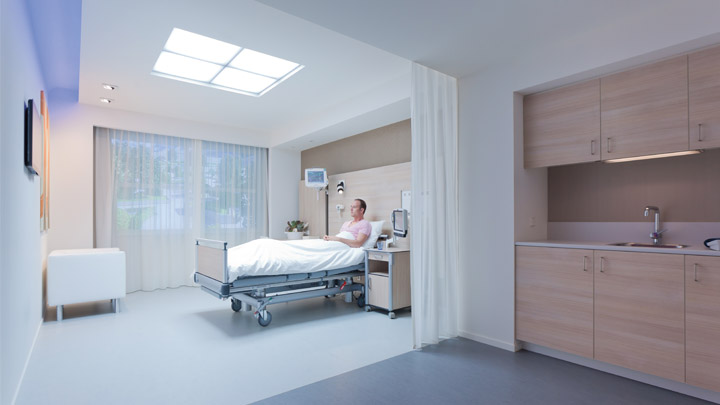 Enfermeira num quarto com uma luz suave escuta atentamente o batimento cardíaco do paciente – iluminação em hospitais