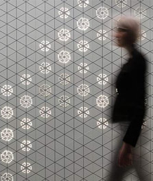 Uma mulher passa junto a uma parede interior decorada com os Padrões Luminosos da Philips – experiência do cliente