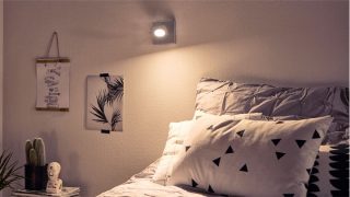 Quarto elegante com holofote LED ajustável criando um ambiente aconchegante, roupa de cama geométrica iluminada e decoração minimalista.